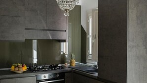 Een moderne keuken met donkere kastjes, een gasfornuis, een oven van roestvrij staal en een groot raam dat natuurlijk licht binnenlaat.