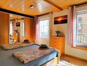 Ein Zimmer mit einem Bett, einem Schminktisch, einem Spiegel und einem Fenster mit Vorhängen.