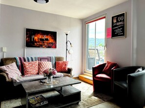 Ein Wohnzimmer mit einer Couch, einem roten Sessel, einem Couchtisch und einem Bild eines Kamins.