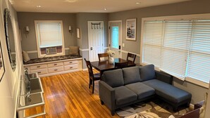 A compact living space with a dining area, a sofa, and a kitchen area.