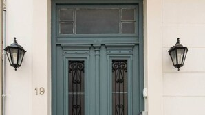 Una porta doppia di colore verde scuro, con due vetri e una maniglia in ottone.