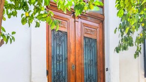 Eine hölzerne Doppeltür mit aufwendlicher Metallverzierung, eingebaut in ein Gebäude mit weißen und hellblauen Wänden.