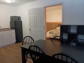 Eine kleine Küche mit Mikrowelle, Kühlschrank und einem Essbereich mit Tisch und Stühlen.