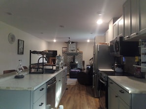A modern kitchen with stainless steel appliances, a brick wall, and a wooden floor.