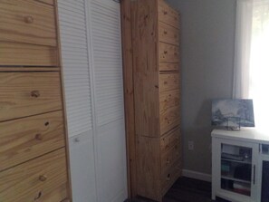 Ein Zimmer mit einem Holzschrank, einem weißen Schrank mit Glastüren und einem gerahmten Bild auf dem Schrank.