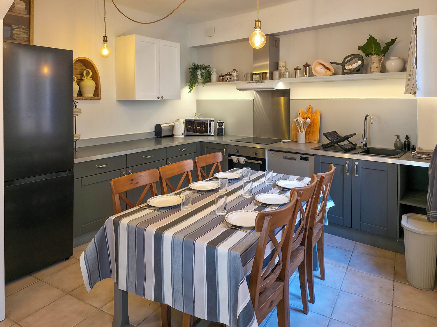 A modern kitchen with a dining table set for four, equipped with a microwave, toaster, and stainless steel range hood.