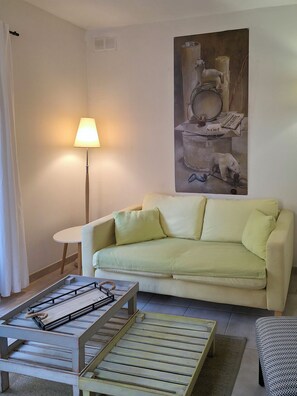 Ein Wohnzimmer mit einer Couch, einer Lampe, einem Couchtisch und einem Bild an der Wand.