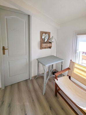 A room with a white door, a small table with drawers, a mirror, and a lamp. - Maison Charlotte - 4★ House with a courtyard, bicycles, 2 km from the beaches (Sainte-Marie-la-Mer)