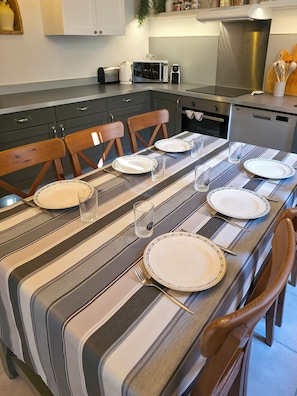 Ein Essbereich mit gestreifter Tischdecke, weißen Tellern und klaren Gläsern, gedeckt für eine Mahlzeit.