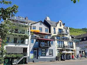 A multi-story building with balconies, a visible storefront, and outdoor seating.