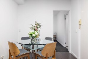 A modern dining area with a glass table, wooden chairs, and a vase of flowers.