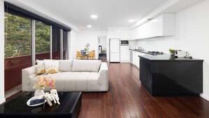 A modern living room with a sofa, coffee table, and a view of the kitchen. - Modern Comfort 2BR  Pool, Gym & Prime Valley Location (Fortitude Valley)