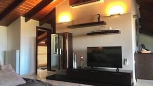 Ein modernes Wohnzimmer mit großem Flachbildfernseher, integrierten Regalen und einem Kamin.