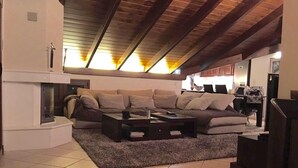 Ein Wohnzimmer mit Ecksofa, Couchtisch und Kamin.