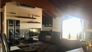 Eine moderne Küche mit Essbereich, integrierten Geräten und einem großen Fenster für natürliches Licht.