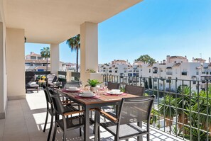 A balcony with a table set for dining, chairs, and potted plants. - Lovely 2-bed 10 Mins Walk From Puerto Banus (Marbella)
