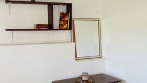 Ein Zimmer mit einem Holzkasten, einem Bücherregal und einem gerahmten Spiegel.