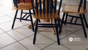 Ein Essbereich mit einem Holztisch, vier Stühlen, einer roten Tür und zwei gerahmten Bildern an der Wand.