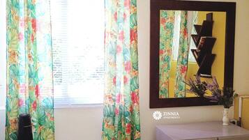 Una habitación con cortinas de flores, un espejo, un tocador y un cartel de Zinnia Apartments.