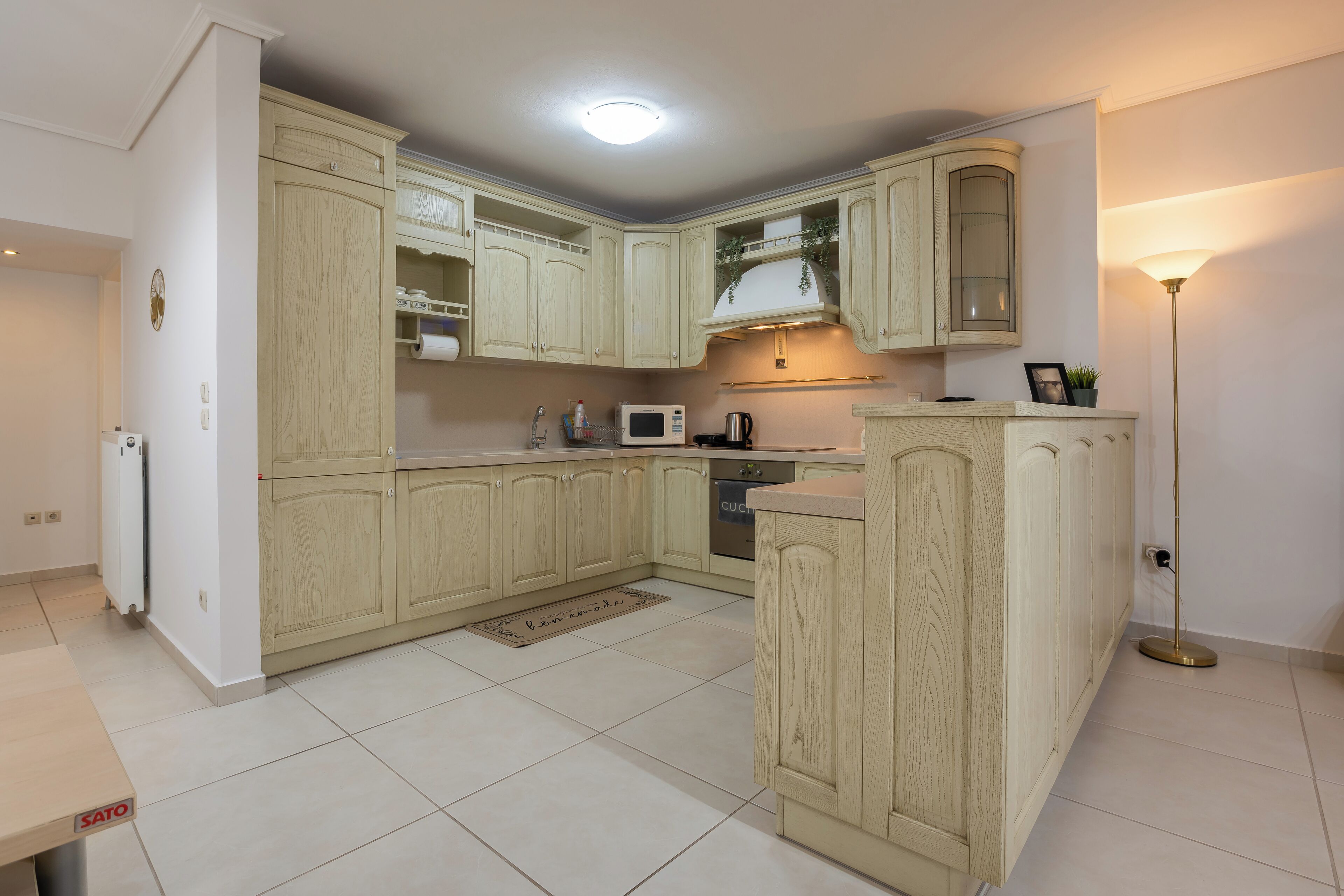 Une cuisine moderne avec des meubles de couleur bois clair, un four à micro-ondes encastré et une cuisinière à gaz.