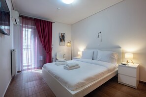 A modern hotel room with a large bed, bedside tables, a chair, a window with curtains, and a wall-mounted air conditioner. - 2BR hot tub near metro  (Athens)