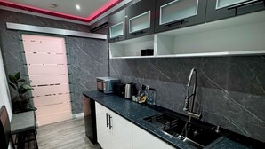 A modern kitchen with white cabinets, a black countertop, and a built-in sink. - Suite 1 Private Jacuzzi Spa Hot Tub & Sauna (Sheffield)