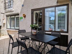 Une terrasse extérieure avec une table et des chaises, une plante en pot et une fenêtre donnant sur un beau paysage.