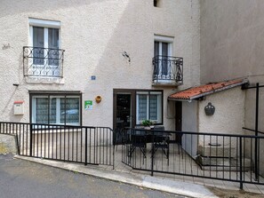 A two-story building with a balcony, a door, and a small outdoor seating area with a table and chairs. - Modern family house near Puy-en-Velay with Wifi (Vals-prés-le-Puy)