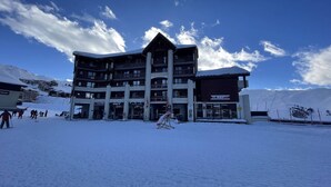 Ein mehrstöckiges Hotel mit einer Skipiste im Hintergrund.