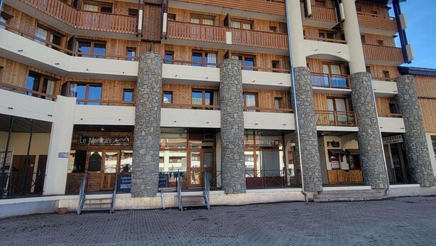 Ein mehrstöckiges Hotel mit hölzernen Balkonen, steinernen Säulen und einem Schild mit der Aufschrift 'Le Morica'.
