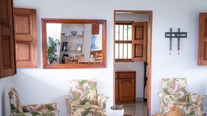 A living room with two floral armchairs, a coffee table, and a wooden cabinet. - Casa linda between mountains and Café: Landscapes, birds and flowers (Andes)
