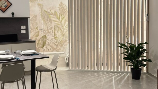 Zona de menjador moderna amb un disseny minimalista, amb una taula preparada per a quatre, dues cadires i una planta en test.