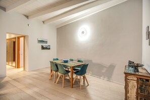 A dining area with a wooden table and chairs, a light fixture on the wall, and a door leading to another room. - 2 Bedrooms & 2 Bathrooms Monti (Roma)