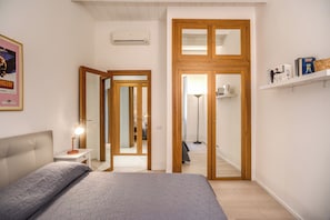Ein Schlafzimmer mit Bett, Nachttisch, Lampe, Kleiderschrank und Spiegel.