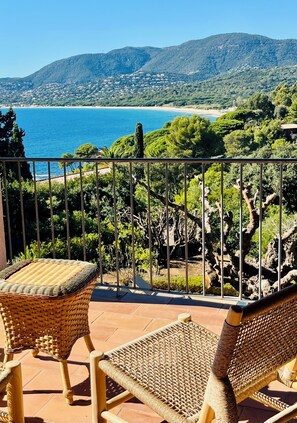 A balcony with wicker furniture overlooking a coastal landscape with mountains and a beach. - Villa Doufer, exceptional sea view, beach 100m away, sleeps 8. (la croix valmer)