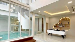 Ein modernes Interieur mit Pool, Klavier und Billardtisch.