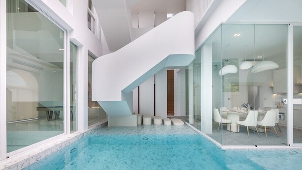 Ein moderner, überdachter Pool mit Glaswand und weißer Treppe.