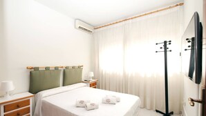 Une chambre d’hôtel équipée d’un lit, d’une table de chevet, d’une lampe, d’un climatiseur et d’un porte-manteau.