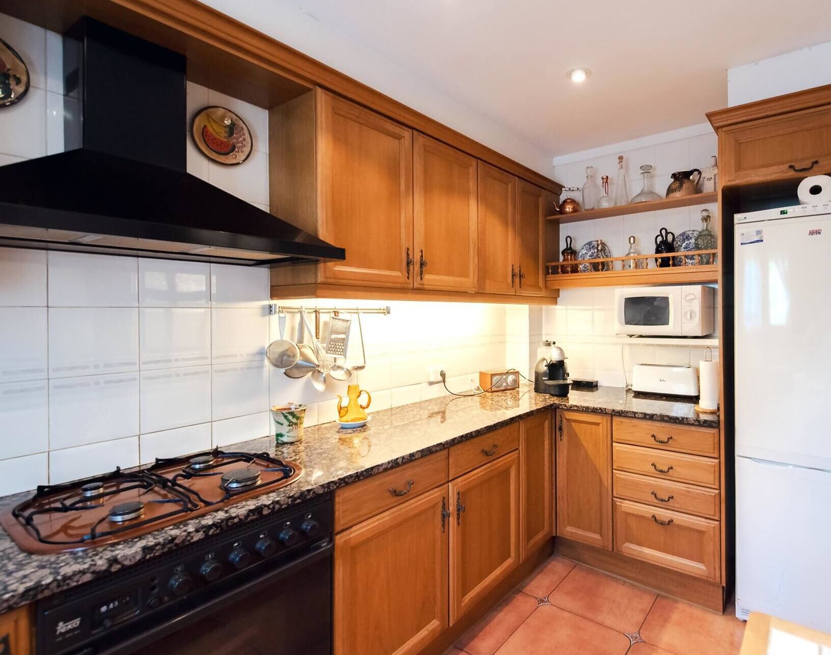 A kitchen with wooden cabinets, a gas stove, a microwave, and a refrigerator.