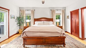 Una camera da letto con un letto di legno, una ventola a soffitto e un'ampia finestra con tende.