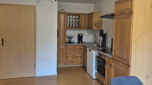 Una cocina compacta con armarios de madera, una cafetera y un lavavajillas.