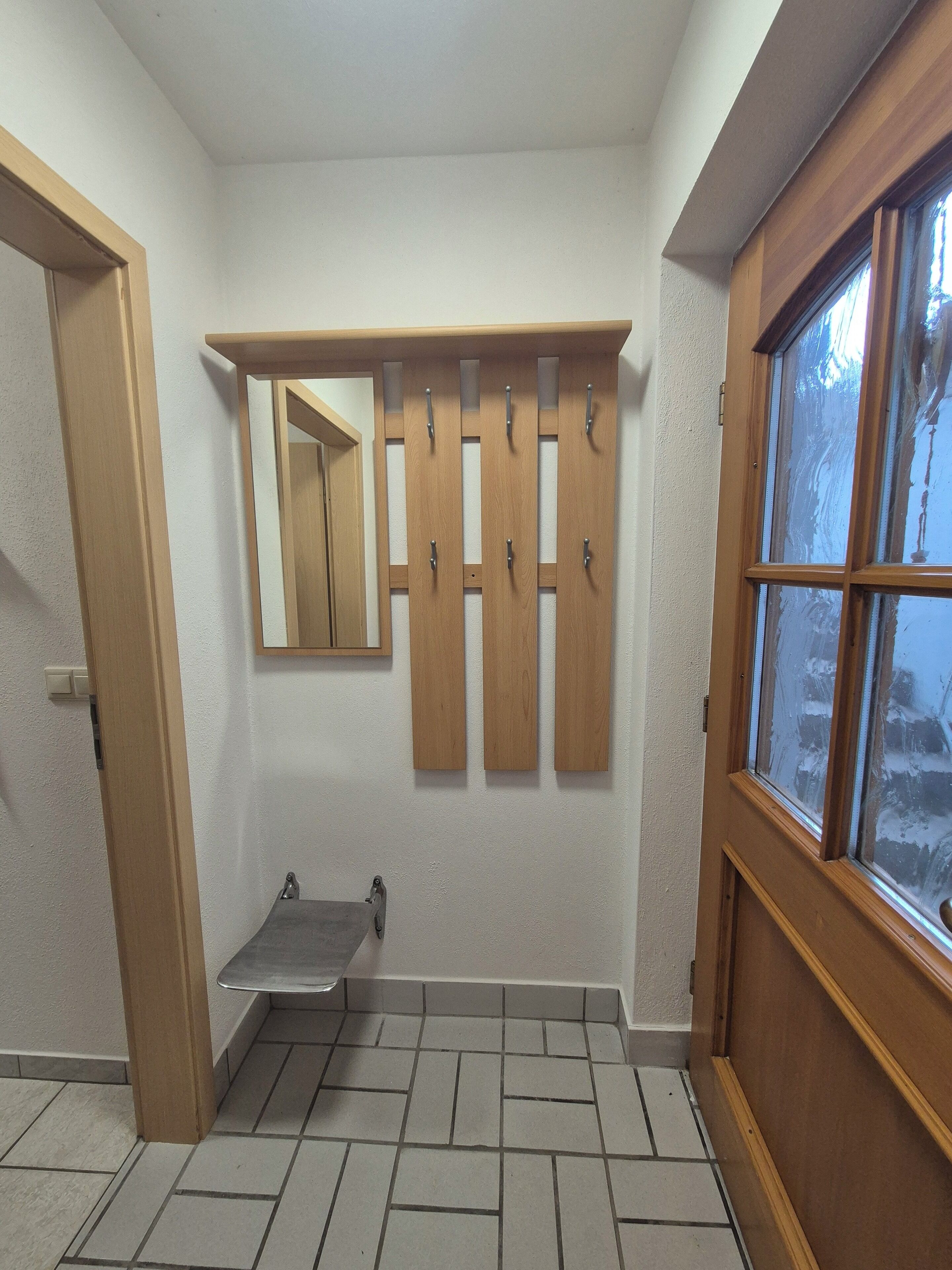 Un baño con piso de baldosas, un mueble de tocador de madera y un ventanal con vidrio esmerilado.