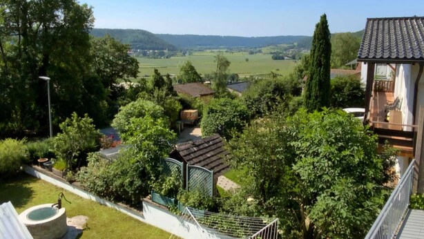 Una propiedad residencial con jardín, un pequeño estanque y vistas al campo.