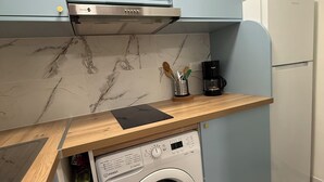 Una cucina compatta con lavatrice integrata, macchina del caffè e forno a microonde.