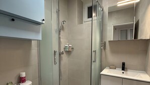 Un bagno moderno con doccia vetrata, un water e un lavabo con specchio sopra.