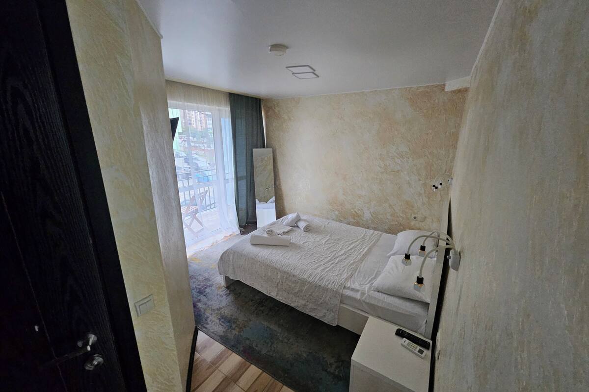 Une chambre d’hôtel avec un lit, une table de chevet et une vue sur l’extérieur.