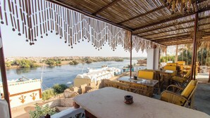Une terrasse avec vue sur une rivière, des sièges extérieurs et des décorations suspendues.