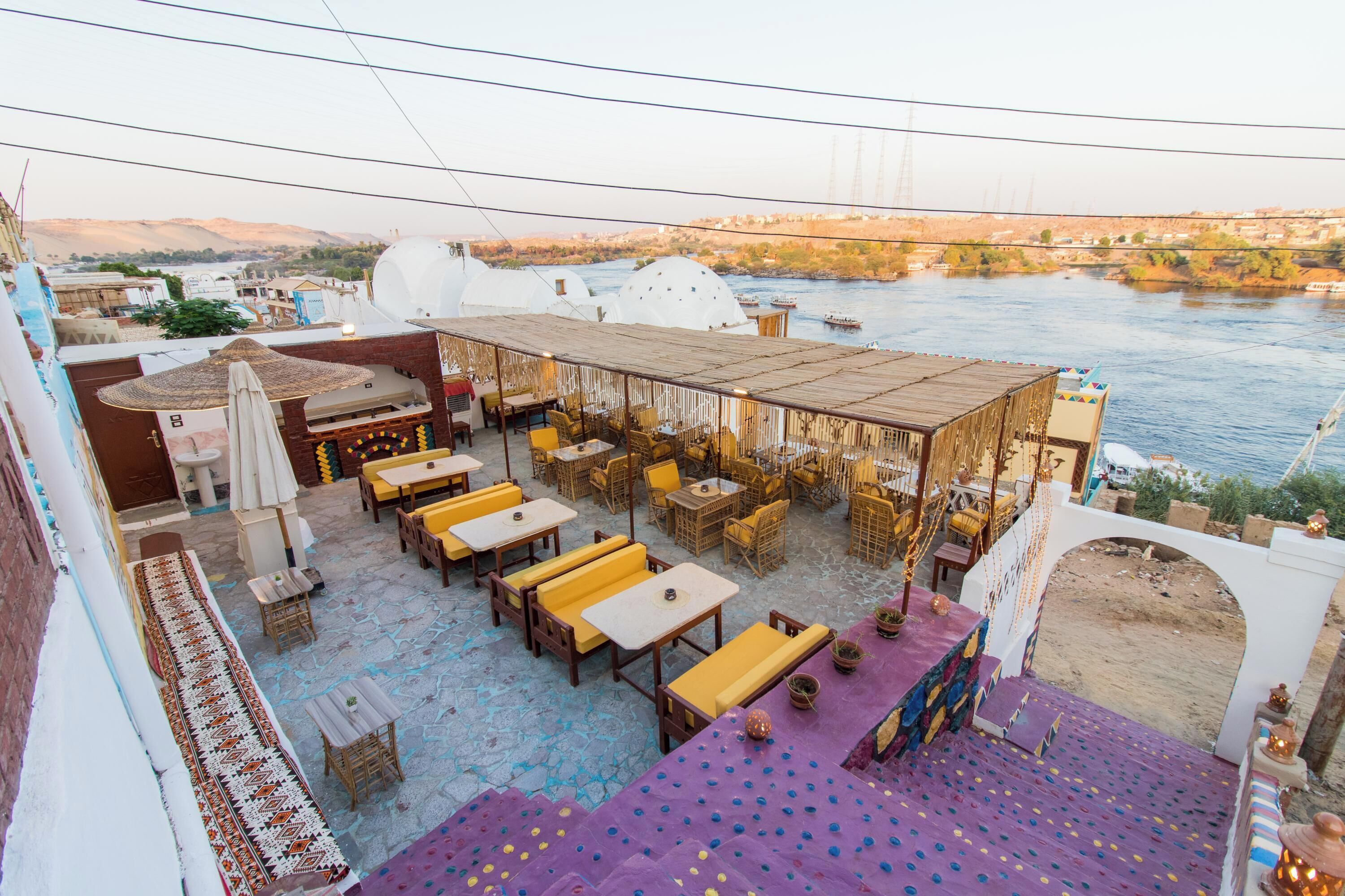 An outdoor seating area with tables and chairs, overlooking a river.