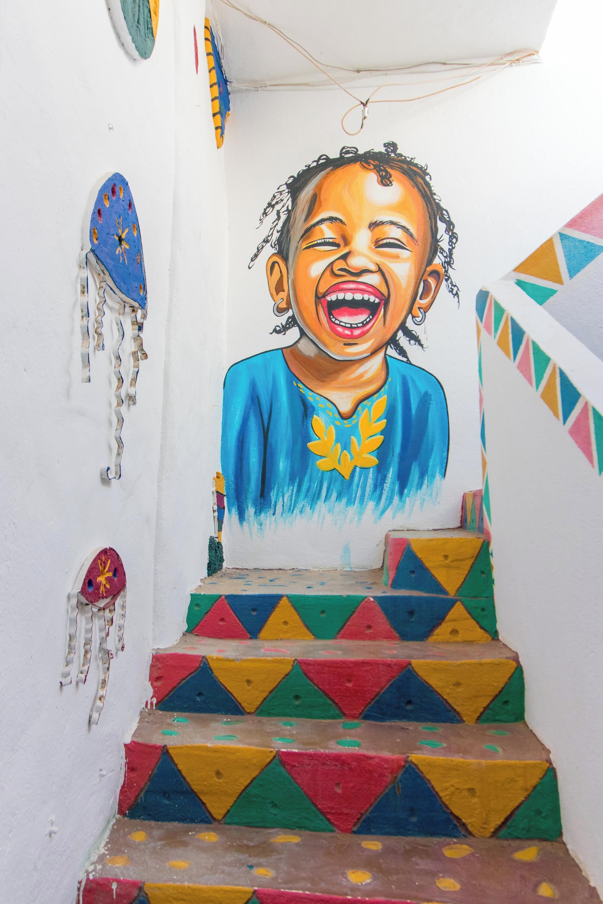 A staircase with colorful geometric patterns and a mural of a person.