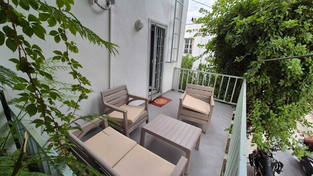 A balcony with outdoor furniture, including two sofas and a table, surrounded by greenery.